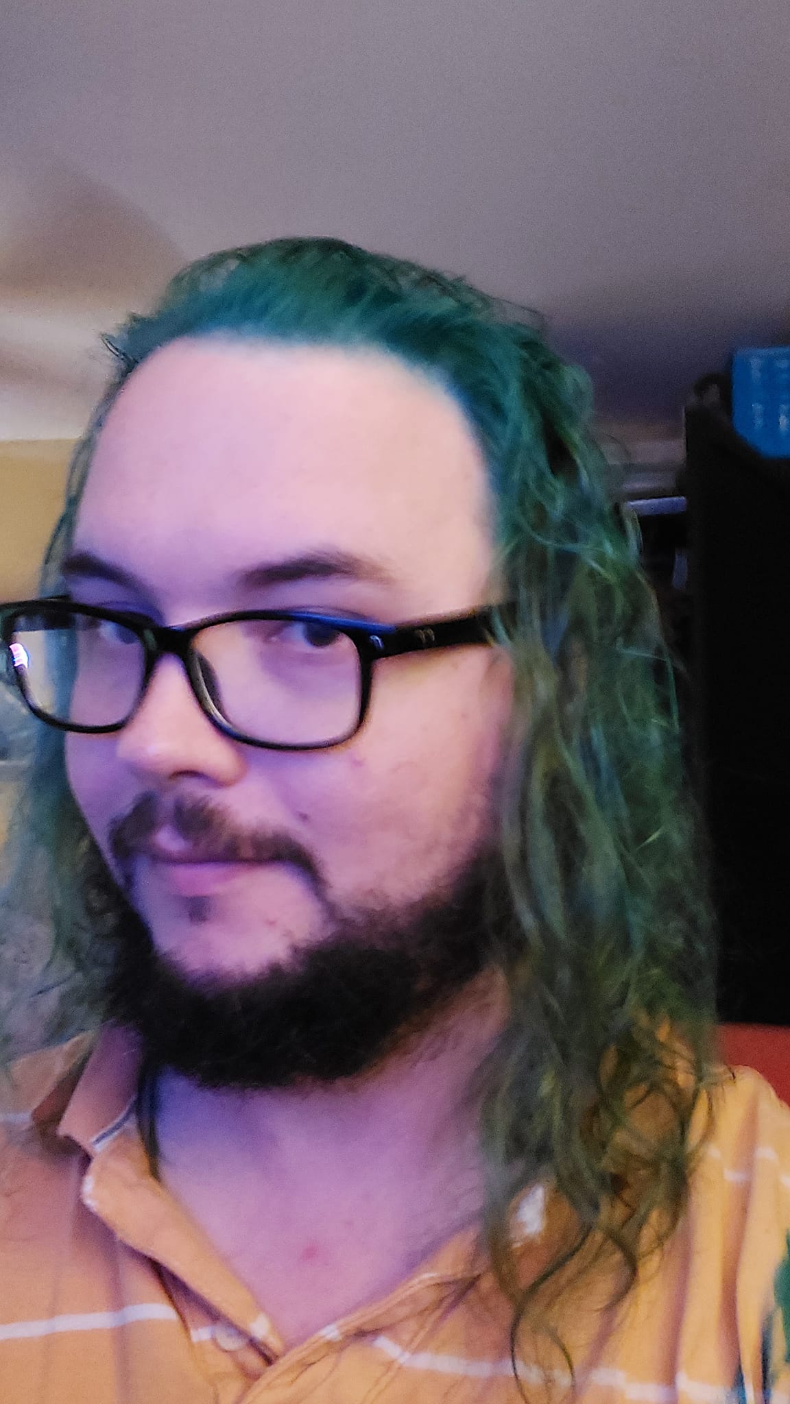 A man with long green hair sits in a computer chair, photo 1